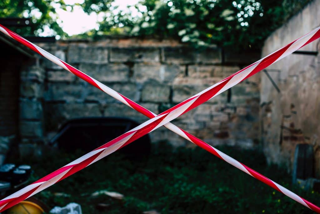 Red and white police tape in a criss cross in front of a site 
